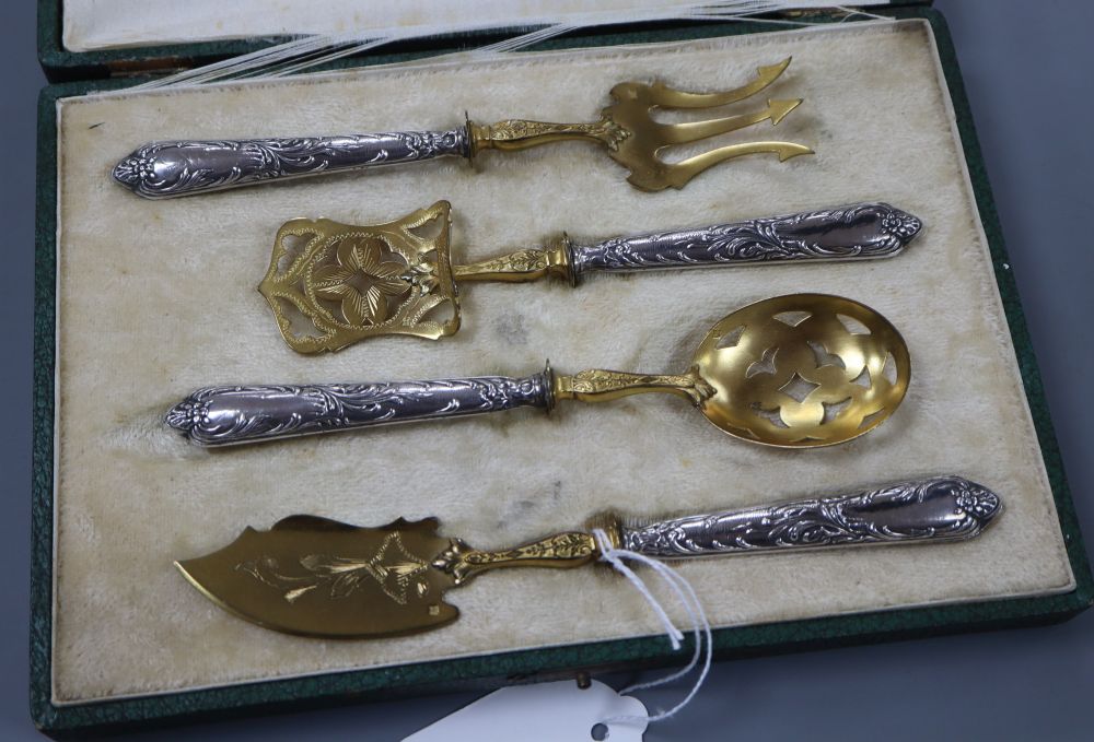 A cased early 20th century French parcel gilt white metal four piece serving set, longest 18cm, loaded handles.